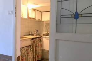Una cucina con mobili bianchi, un fornello e un bollitore.