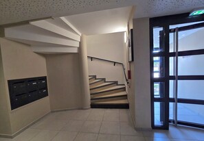 Eine Treppe mit Handlauf, eine Tür mit Glasfenster und ein Briefschlitz an der Wand.