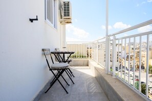 Un balcon avec une balustrade blanche, une table et deux chaises.