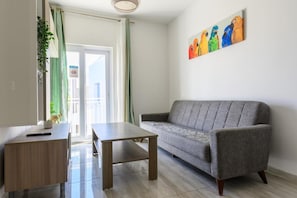 En moderne stue med en grå sofa, et træbord og et maleri af farverige papegøjer på væggen.