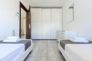 Habitación de hotel con dos camas, un armario, un espejo y una puerta.
