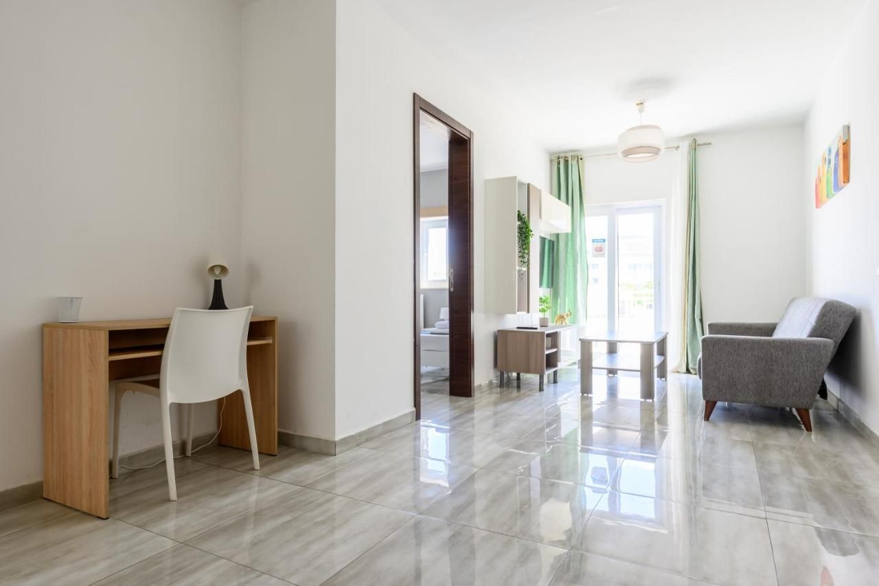 Un soggiorno moderno con una scrivania in legno, una sedia bianca, un divano grigio e un tavolino.