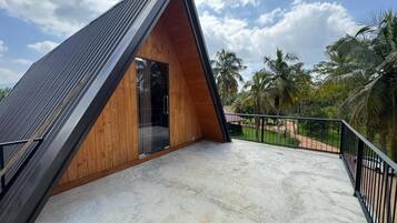 A modern, triangular-shaped building with a balcony and a view of palm trees.