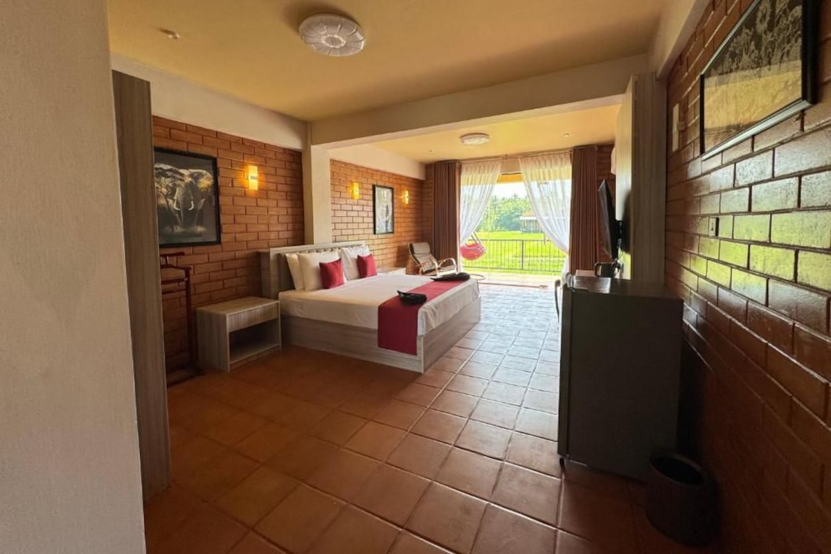 Habitación de hotel con cama, una mesita, televisor y balcón con vistas.