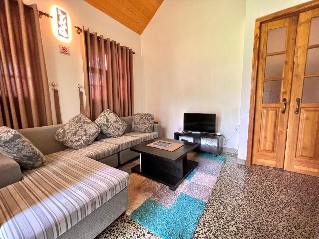A living room with a sofa, a coffee table, a television, and a wooden door.