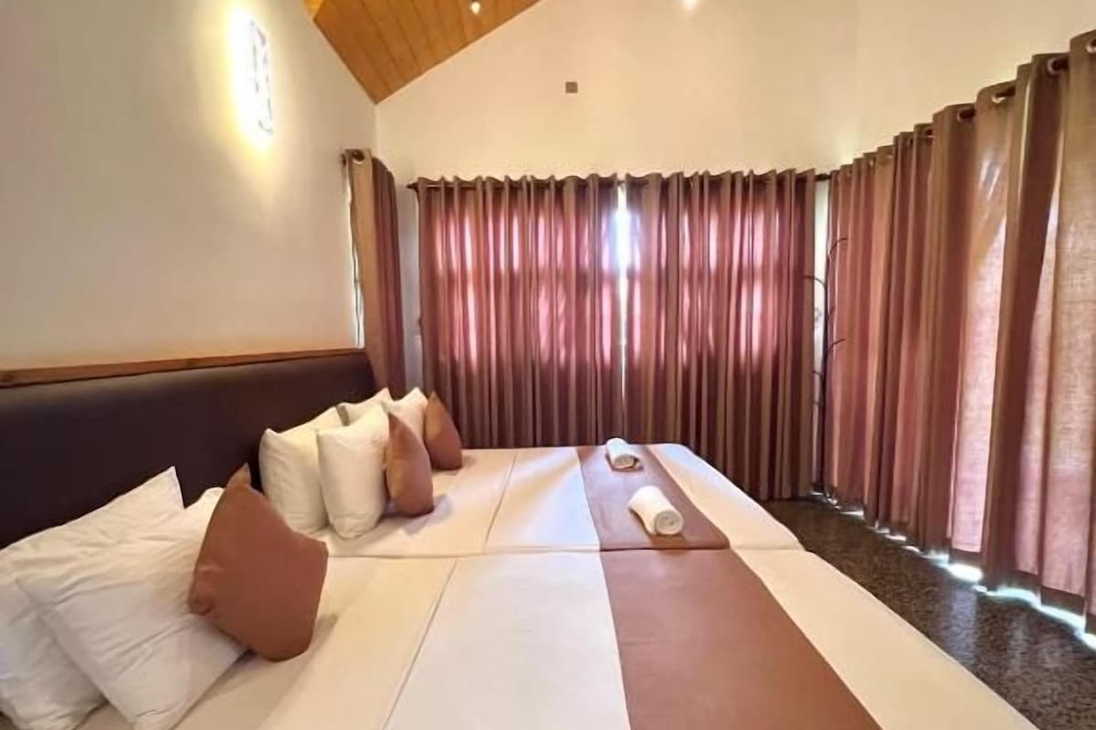 Una habitación de hotel con una cama grande, techo de madera y un ventilador de techo.
