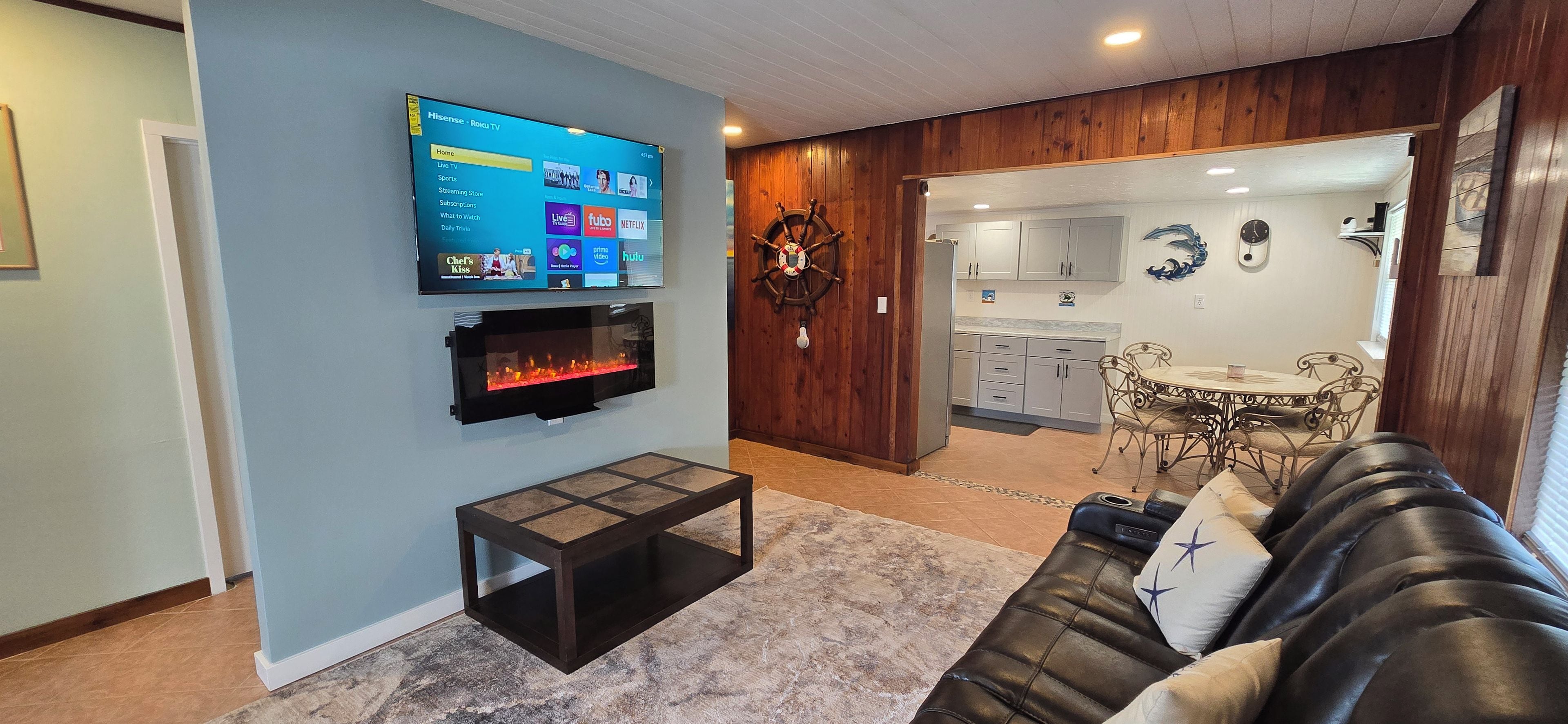 A living room with a TV, fireplace, and a dining area with a table and chairs.