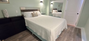 Um quarto com cama, cômoda, espelho e porta.