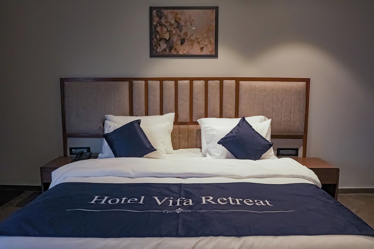 A hotel room with a bed, a headboard, two bedside tables, and a wall-mounted artwork.