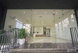 A reception area with a receptionist desk, glass doors, and potted plants. - Hotel Vifa Retreat (Lucknow)