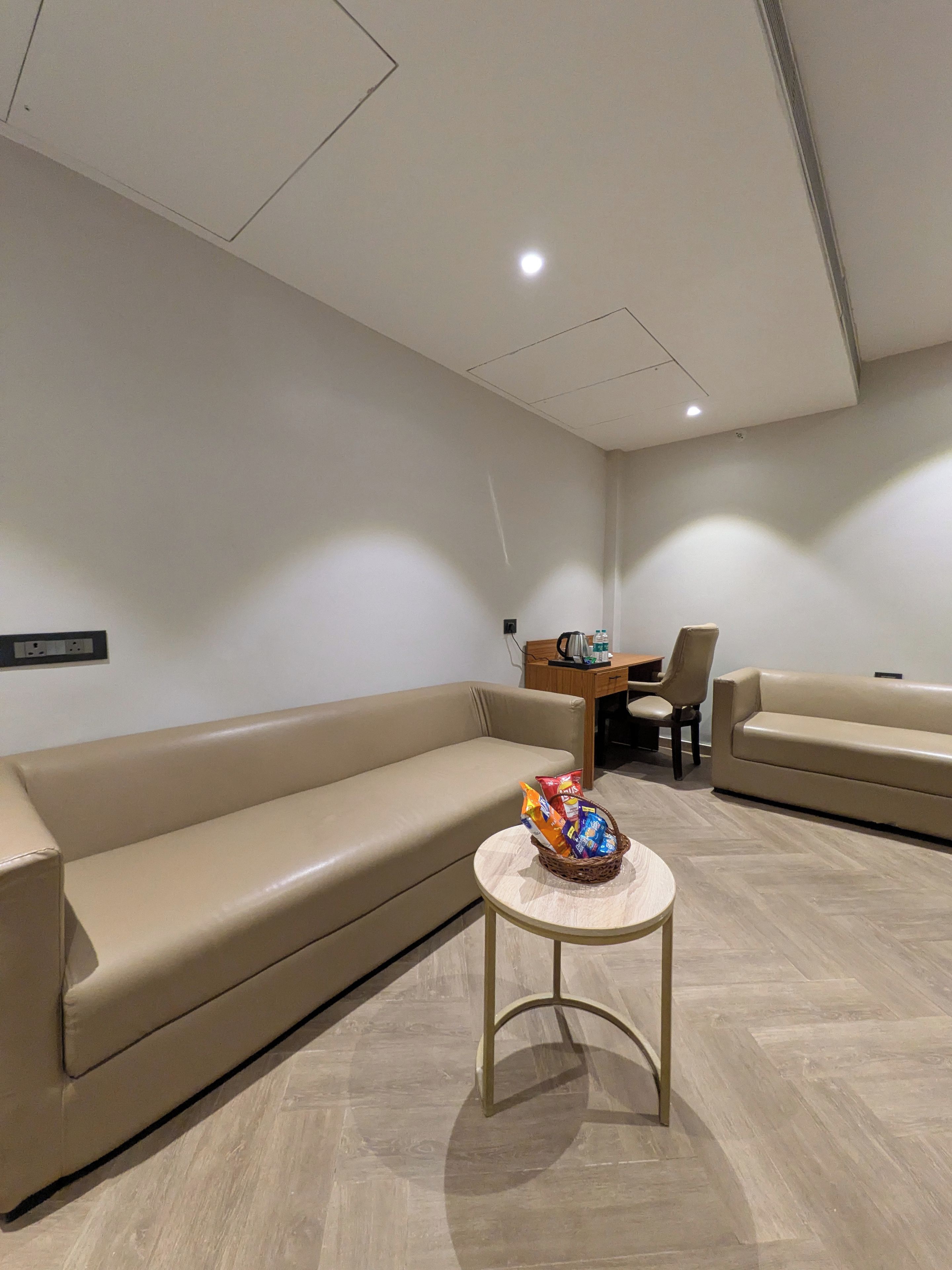 A modern living room with a sofa, a small round table with snacks, and a coffee table.