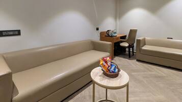 A modern living room with a sofa, a small round table with snacks, and a coffee table.
