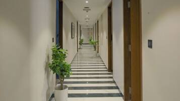 Un pasillo de hotel con piso a rayas, puertas a ambos lados y plantas en macetas.