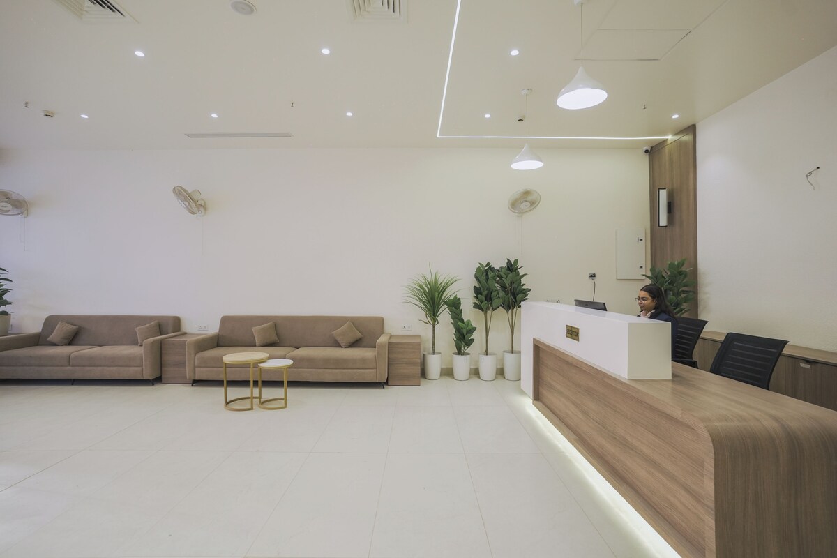 A reception area with a wooden reception desk, two sofas, a small table, and potted plants.