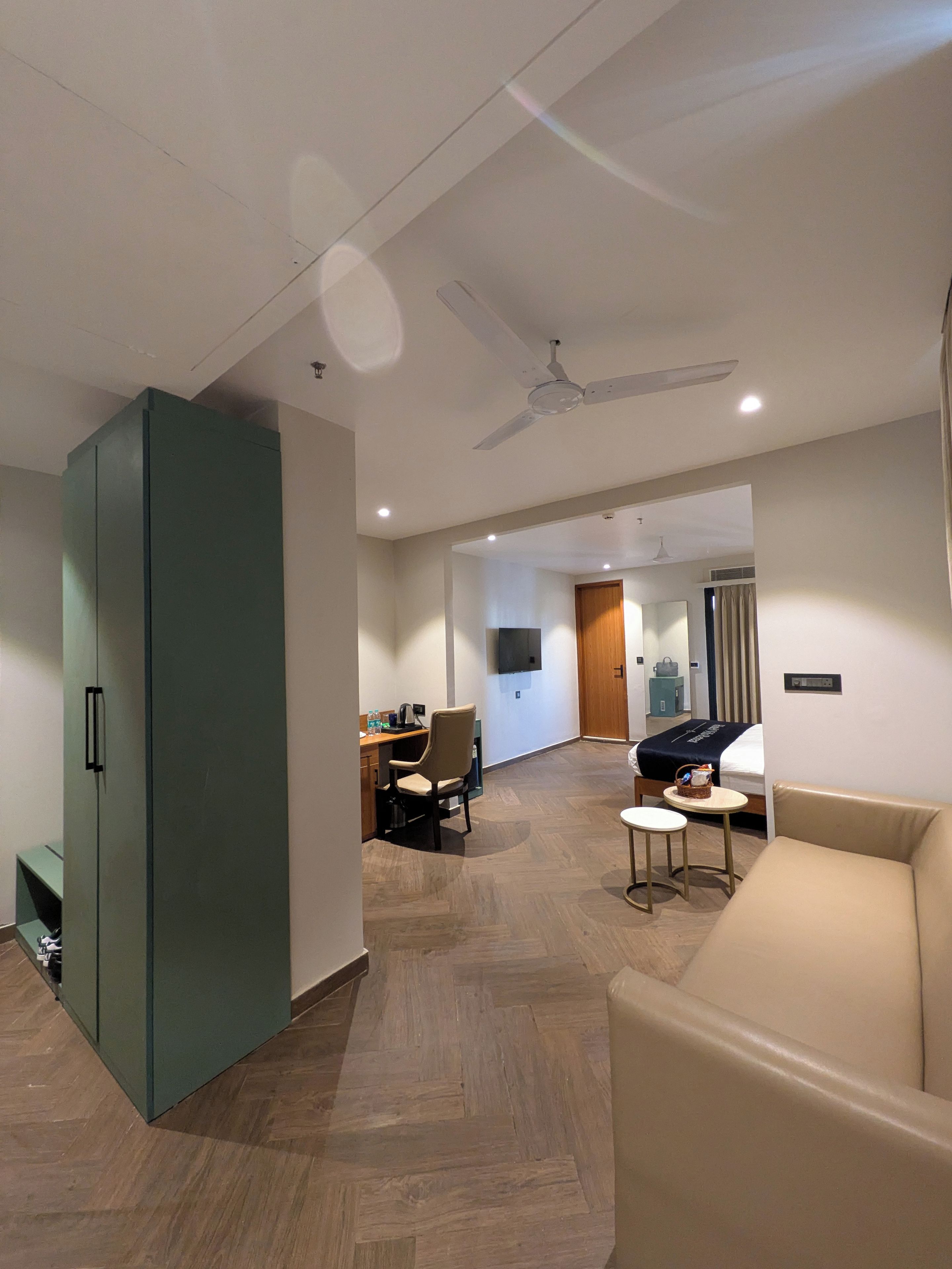 Habitación de hotel con un armario grande, un sofá, un escritorio con una silla y un televisor.