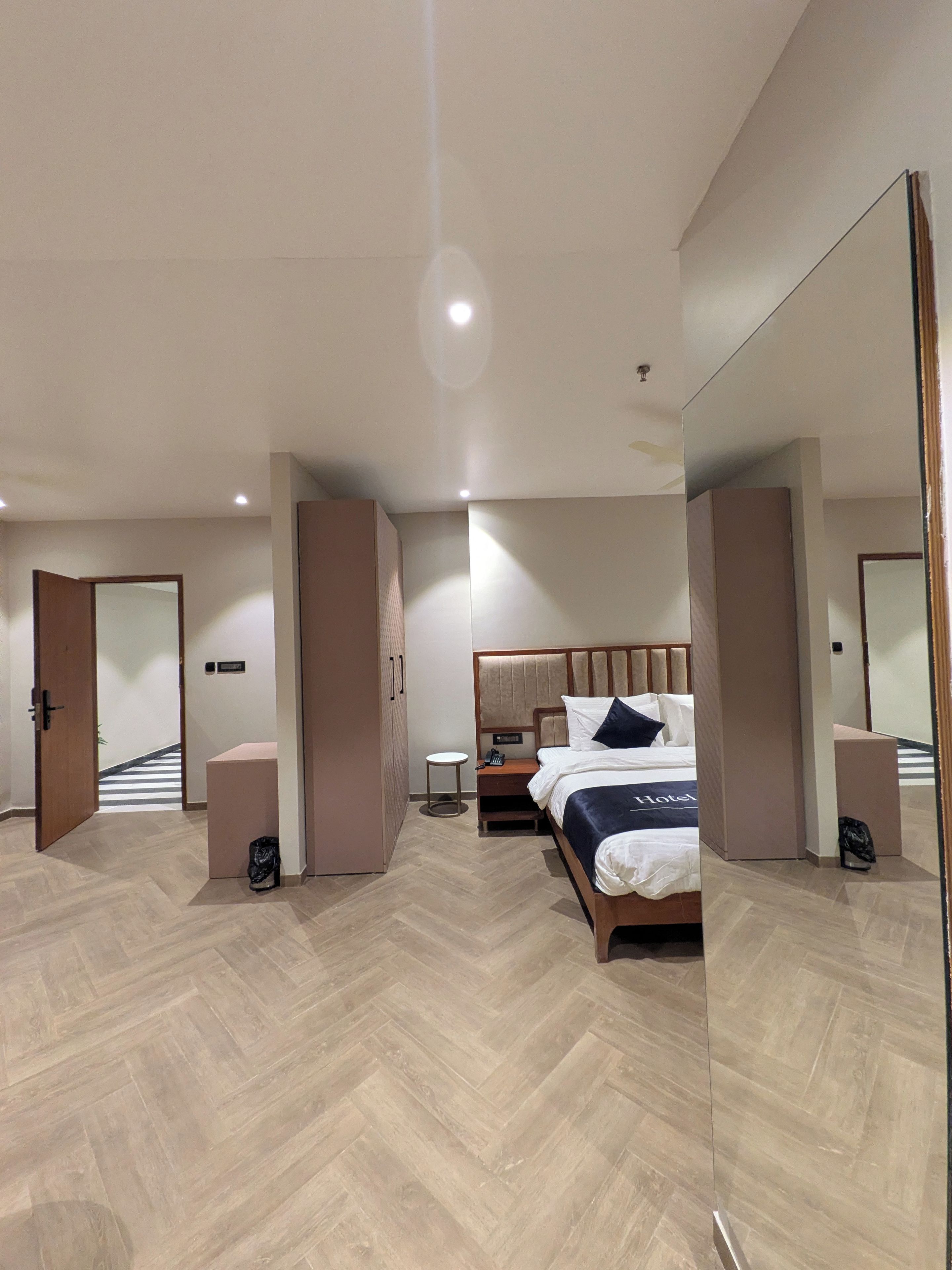 Una habitación de hotel moderna con una cama grande, una mesita de noche y un espejo.