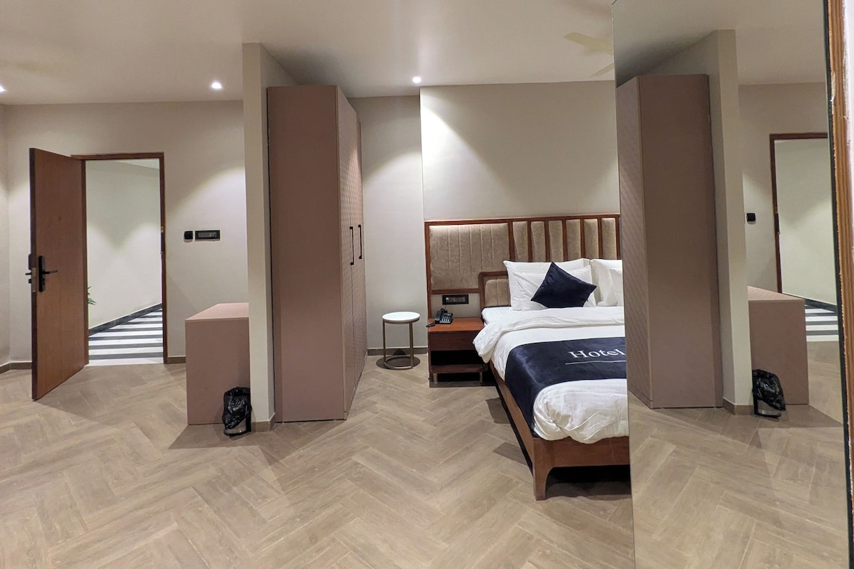 A modern hotel room with a large bed, a bedside table, a nightstand, and a mirror.