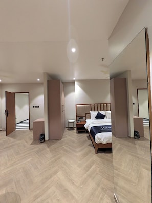 A modern hotel room with a large bed, a bedside table, a nightstand, and a mirror. - Hotel Vifa Retreat (Lucknow)