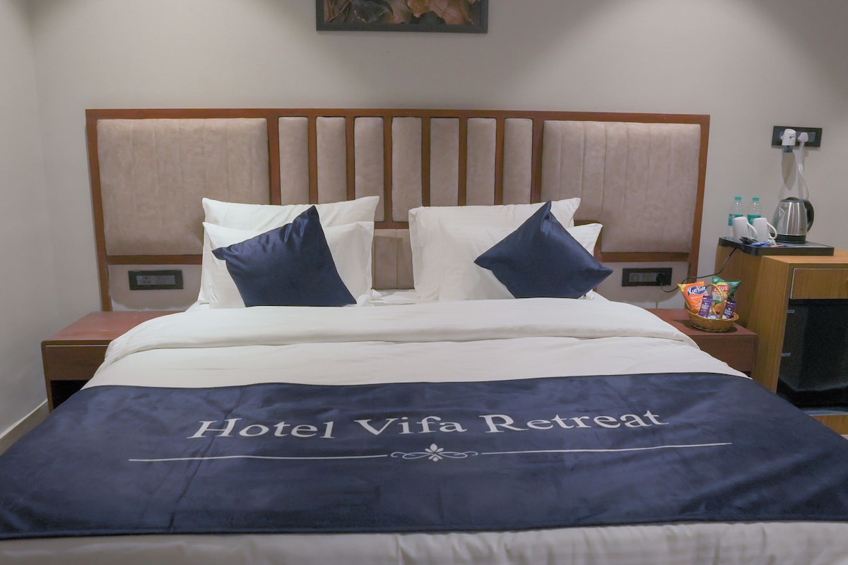 A hotel bed with a headboard, pillows, and a blanket with the text 'Hotel Vifa Retreat'.