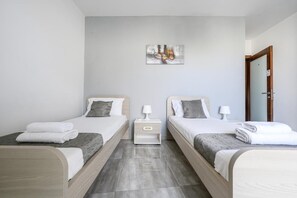Ein Hotelzimmer mit zwei Betten, einem Nachttisch, einem Wandbild und einer Tür.