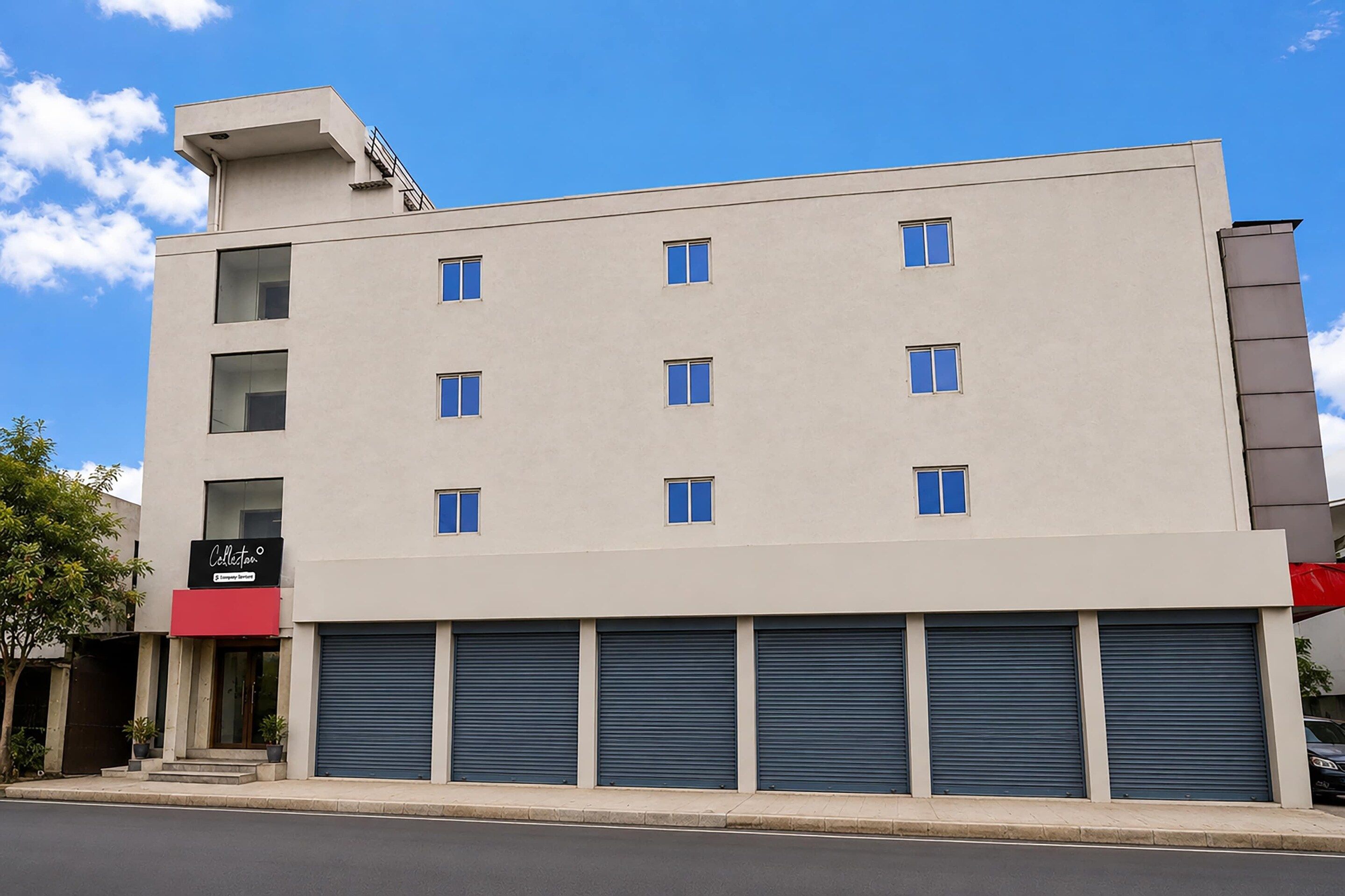 A multi-story building with a flat facade, several windows, and a ground-level garage with closed shutters.