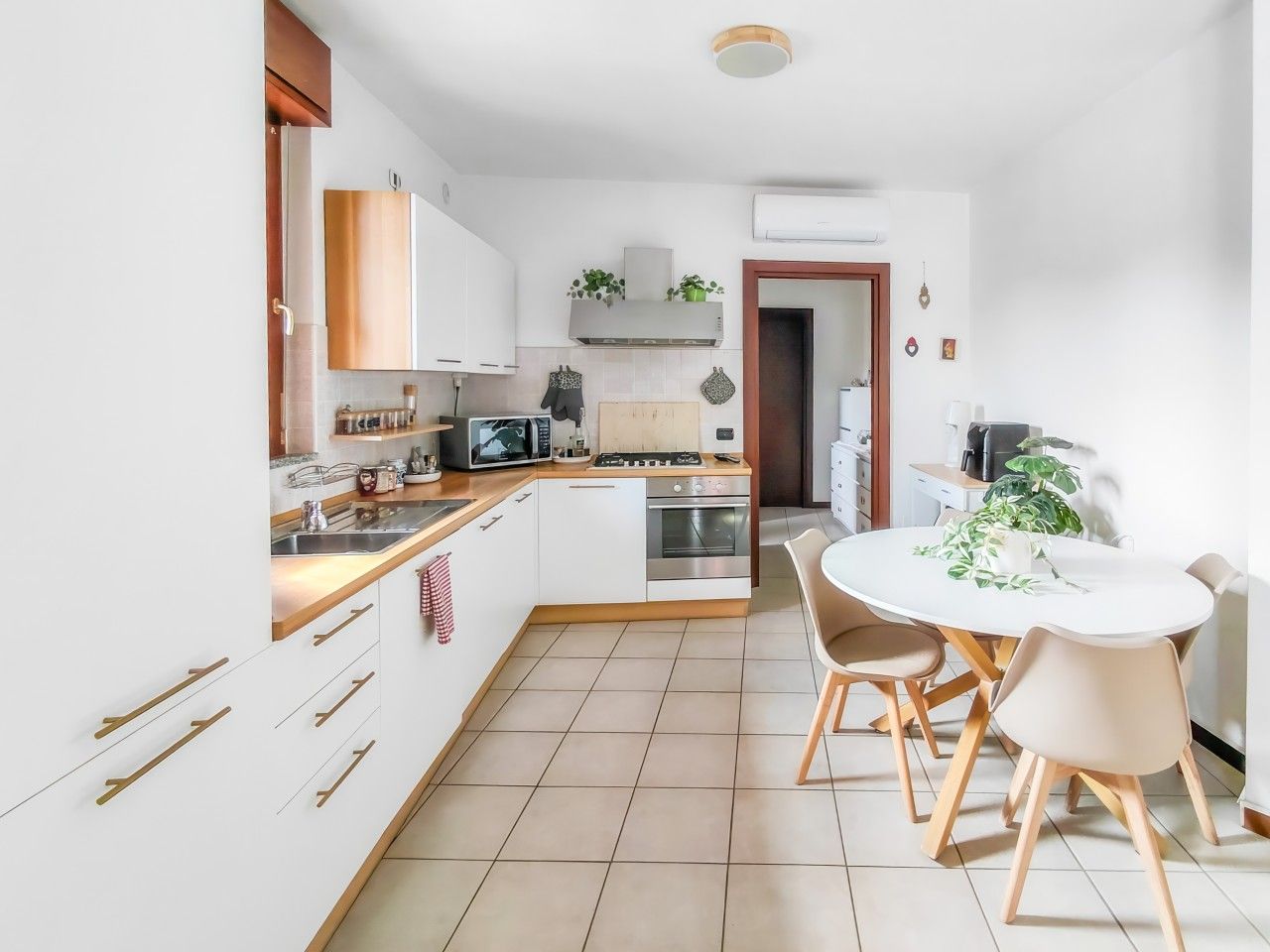 Una cucina moderna con mobili bianchi, elettrodomestici in acciaio inossidabile e un'area pranzo con un tavolo rotondo e sedie.