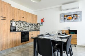 A modern kitchen with wooden cabinets, a black countertop, and a geometric backsplash. - ATLANTIC COURT F8 (Msida)