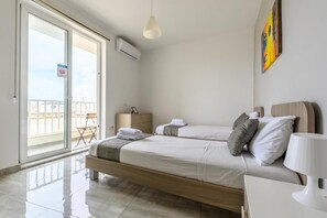 A hotel room with a balcony, a bed, a bedside table, and a chair. - ATLANTIC COURT F8 (Msida)
