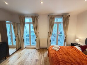 Una camera d'albergo con un letto, una scrivania e vista sul balcone esterno.