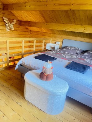 A cozy wooden cabin bedroom with a bed, pillows, a small table, and a stuffed toy. - New Listing (Céreste-en-Luberon)
