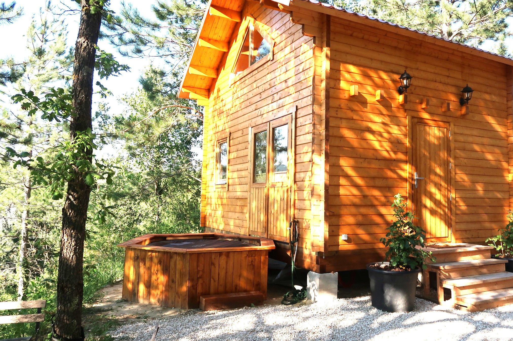 Una cabaña de madera con un porche, un jacuzzi y una maceta.