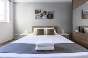 A modern bedroom with a large bed, a bedside table with a lamp, and a wall-mounted artwork. - ATLANTIC COURT F9 (Msida)