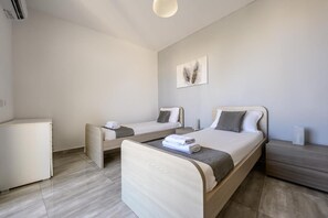 A modern bedroom with a single bed, a sofa, and a small cabinet. - ATLANTIC COURT F9 (Msida)