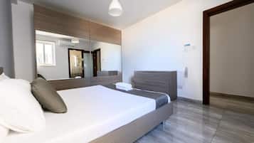 A modern bedroom with a large bed, a bedside table, a mirror, and a wardrobe.