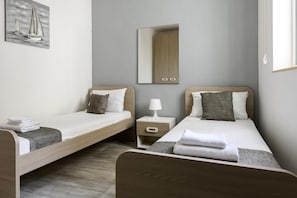 Et hotelværelse med to senge, et natbord med lampe, et spejl og et billede på væggen.