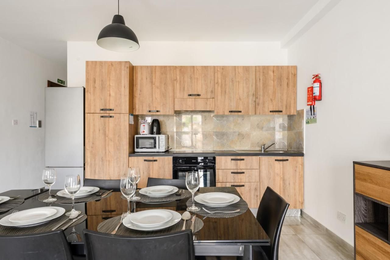 Una cucina moderna con mobili in legno, un forno a microonde e un piano cottura. C'è un tavolo da pranzo apparecchiato con piatti e bicchieri.