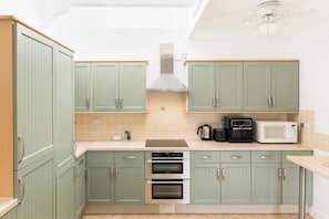 A kitchen with green cabinets, a stove, an oven, a microwave, and a ceiling fan. - Charming Historic 2 Bed & Parking|Stroud Hill View - Pass the Keys (Stroud)