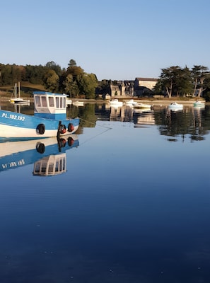 Un cos d'aigua tranquil·la amb barques amarrades, un cel serè i edificis al fons.