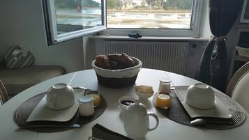 Ein Frühstückstisch, gedeckt mit einem Brotkorb, Teekanne, Tassen und einer Milchkaraffe.