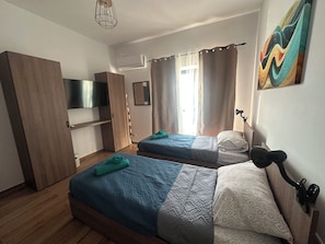 Un dormitorio con dos camas, un televisor, un armario y un cuadro.