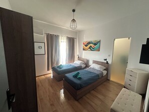 Un dormitorio con dos camas, una lámpara de techo, un cuadro y un radiador.