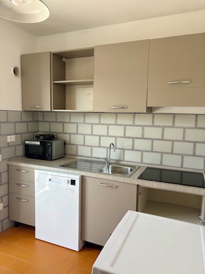 A kitchen with a dishwasher, microwave, sink, and cabinets. - New Listing (Portoferraio)