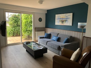 Ein Wohnzimmer mit einem grauen Sofa, einem braunen Ledersessel, einem Couchtisch und einem Gemälde an der Wand.