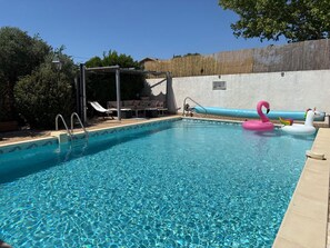 A clear swimming pool with a sunshade structure, lounge chairs, and inflatable toys. - New Listing (La Redorte)