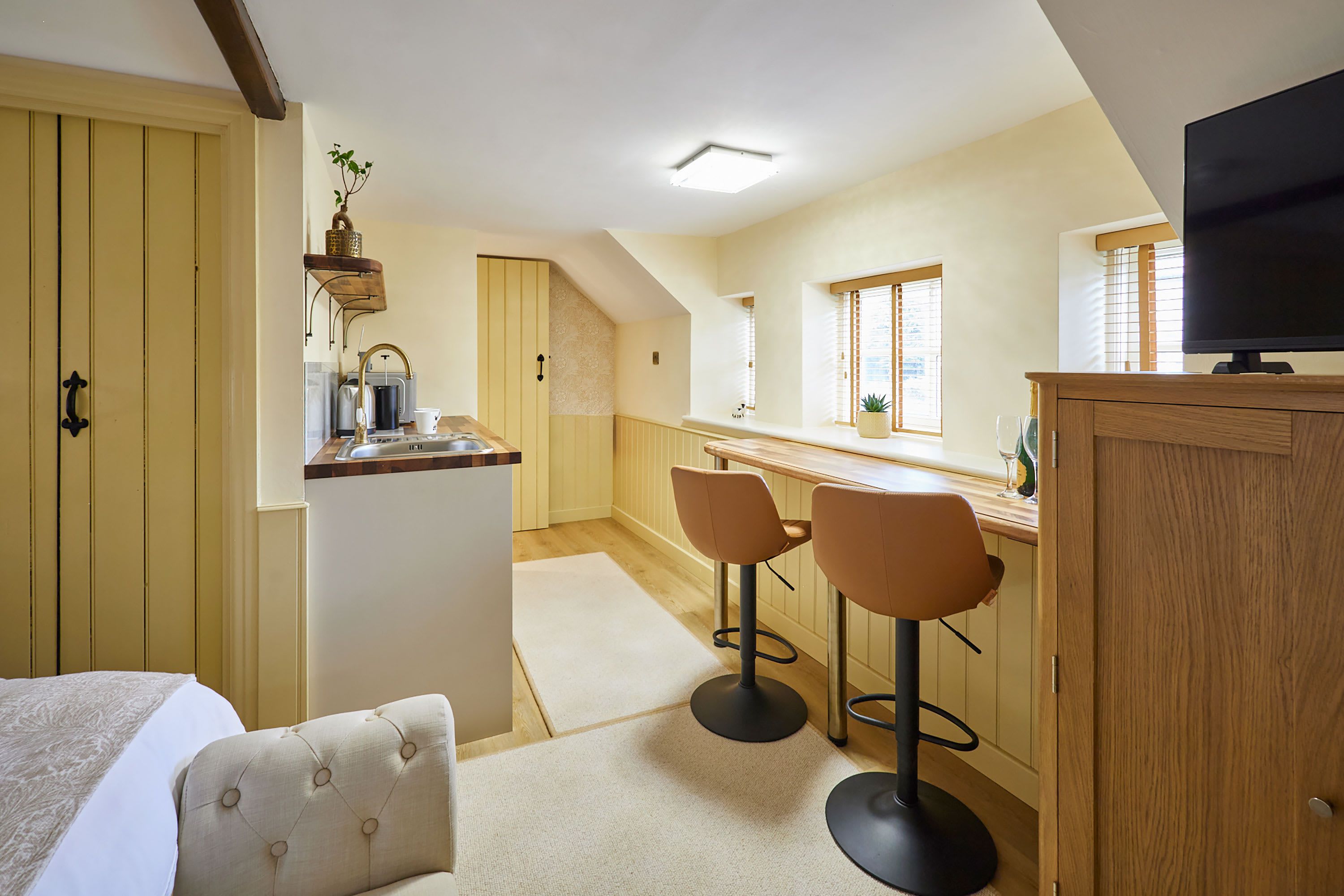 A compact kitchen with a dining area, a television, and a small bar.