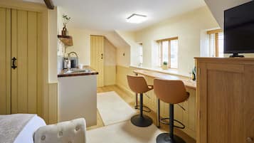 A compact kitchen with a dining area, a television, and a small bar.