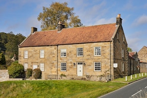A two-story stone building with a red-tiled roof, multiple windows, and a white door. - Host & Stay | Ryedale (Hutton-le-Hole)