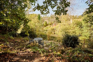 A garden with a table and chairs, surrounded by dense foliage and a stone wall. - Host & Stay | Ryedale (Hutton-le-Hole)