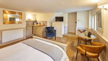 Una habitación de hotel con cama, escritorio con silla, televisión y una pequeña zona de comedor.