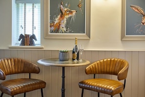 A room with two leather chairs, a round table with a bottle and glasses, and three framed artworks on the wall. - Host & Stay | Ryedale (Hutton-le-Hole)